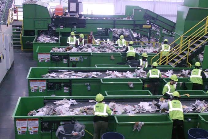 Crew in high visibility vests sorting material along conveyor lines at a waste facility